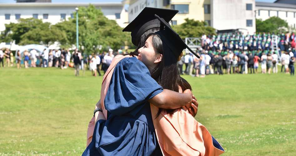 two graduates hugging